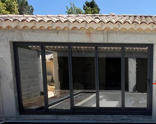 mise en place d’une baie vitrée accordéon en aluminium de 4m sur Cornillon, avec porte de service intégrée et serrure 3 points.