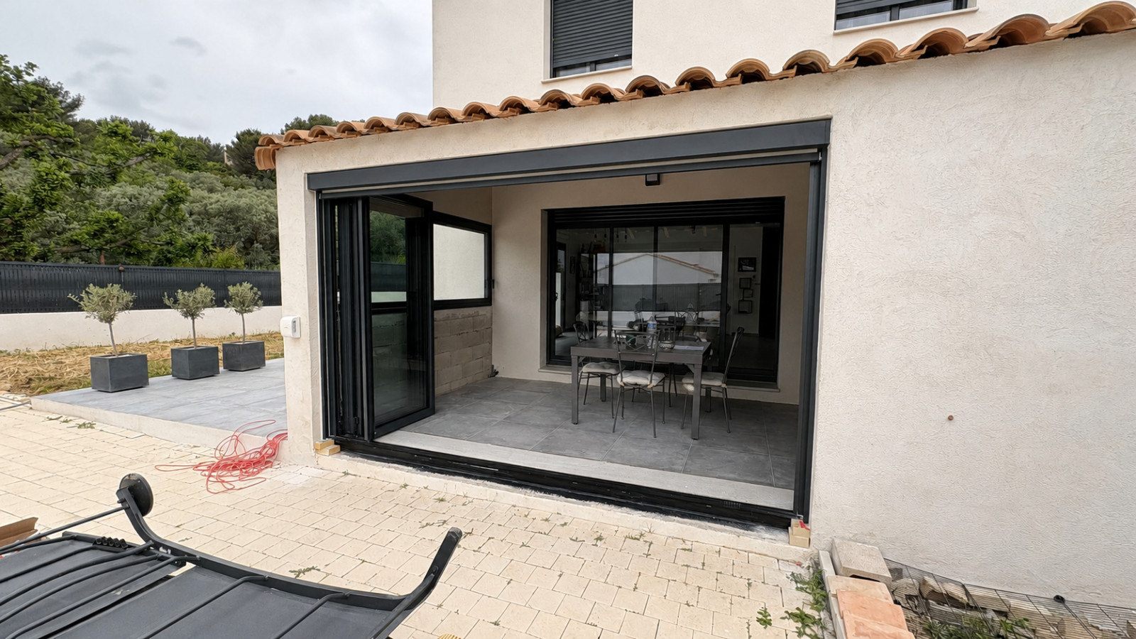 Installation d’une baie vitrée repliable accordéon sur mesure 4 vantaux en aluminium à Château Gombert avec rail encastré et store screen vertical 