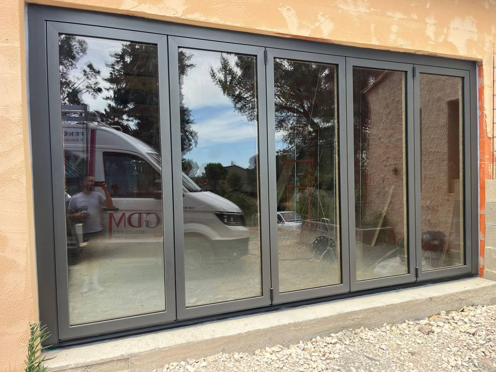 Installation d’une baie vitrée coulissante accordéon en bois/alu à Caumont sur Durance, avec double vitrage feuilleté et rail encastré