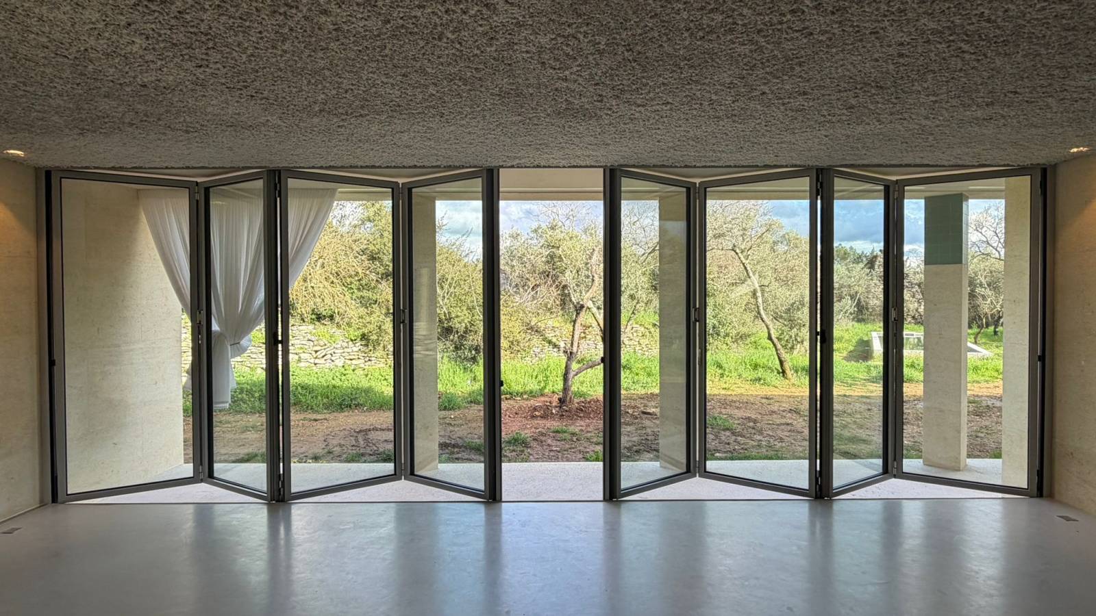 Installation d’une baie vitrée accordéon en aluminium sur mesure avec ouverture centrale extérieure et triple vitrage à Uzès