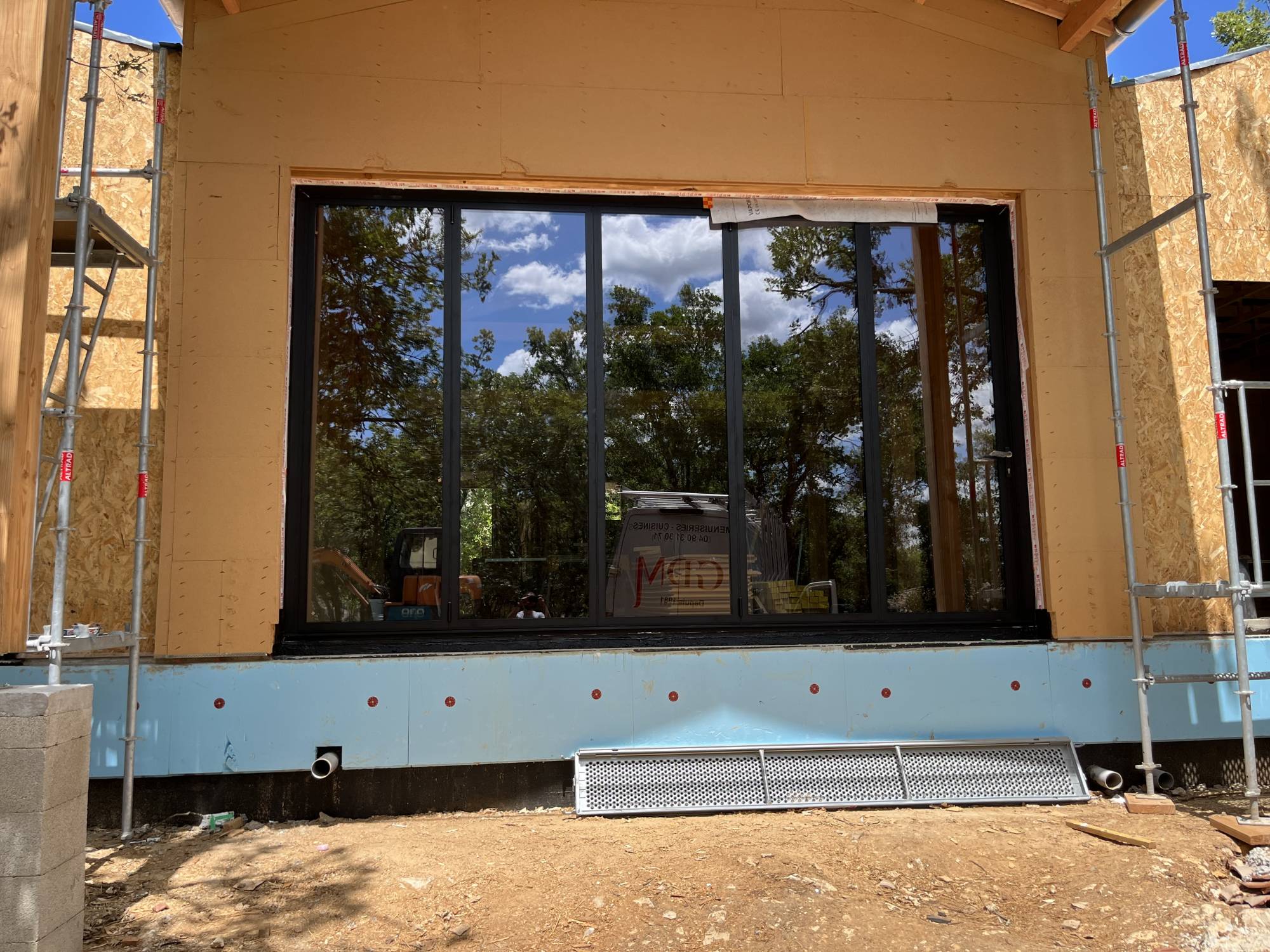 Installation de baie vitrée accordéon pour une fermeture de maison ossature bois à Lavilledieu en aluminium haute de gamme