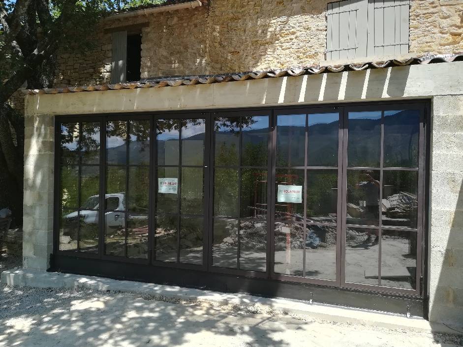 Installation d'une baie vitrée coulissante accordéon à Saint Martin de Castillon dans le Luberon proche de Viens avec petits bois collés en aluminium