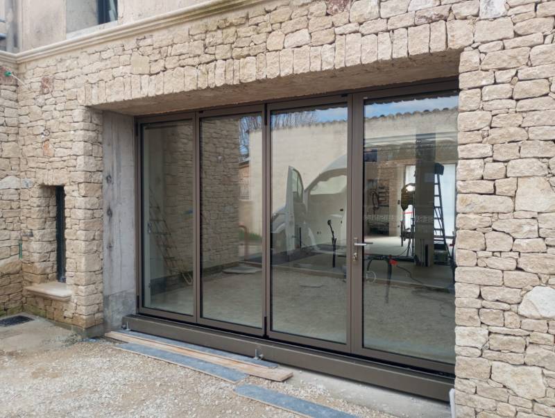 Pose d’une baie vitrée coulissante en accordéon en aluminium sur mesure à Cabrières d’Avignon avec porte intégrée et ouverture extérieure